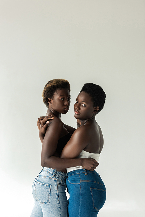 attractive african american women in tops hugging isolated on grey