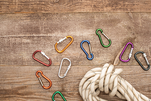top view of colorful carabiners and hiking rope on wooden table