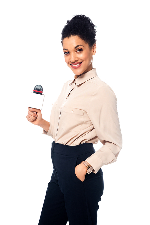 African american journalist with hand in pocket holding microphone,  and smiling isolated on white