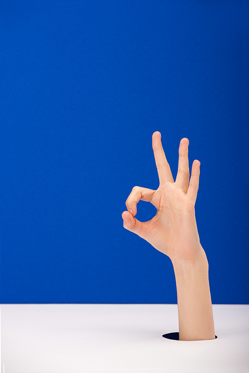 cropped view of woman showing ok sign isolated on blue