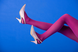 cropped view of model in bright purple tights and heels posing on blue