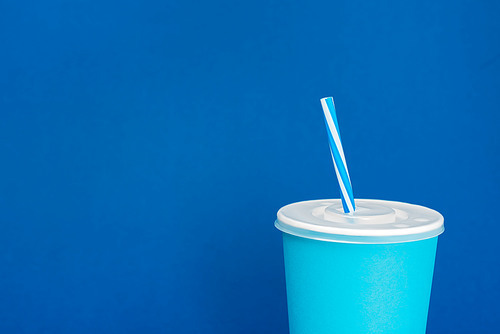 paper cup with soda on blue background with copy space