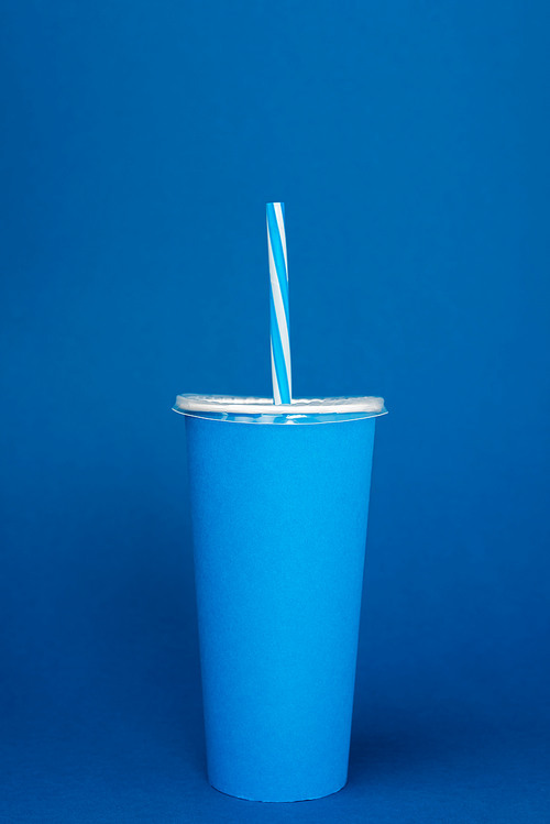 paper cup with plastic straw on blue background