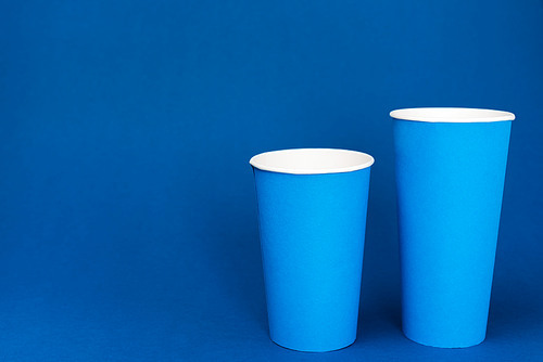 paper cups with soda on blue background with copy space