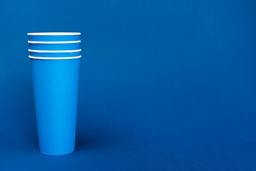bright paper cups on blue background with copy space