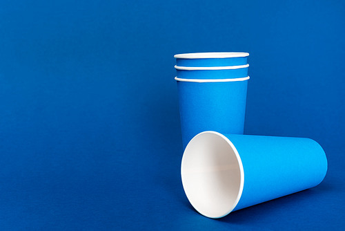 empty paper cups on blue background with copy space