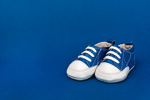 baby shoes on blue background with copy space