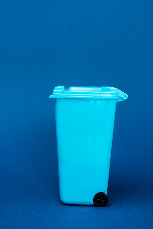 toy trash can on blue background with copy space