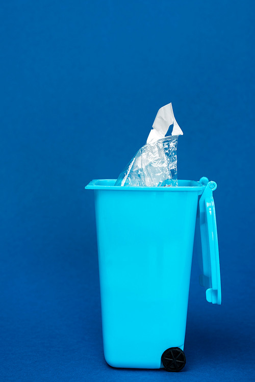 toy trash can with plastic bag on blue background