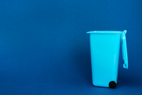 toy trash can on blue background with copy space