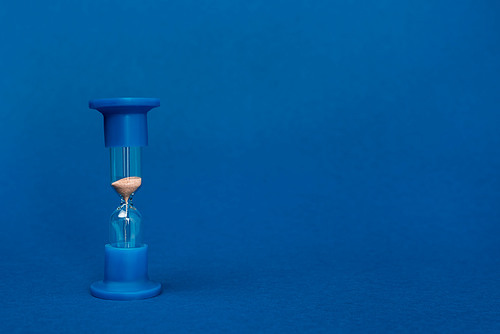 bright and colorful hourglass on blue background with copy space