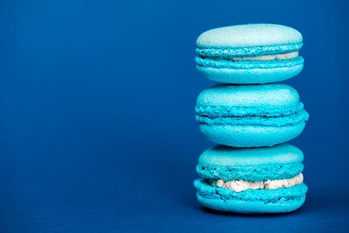 tasty french macaroons on blue background with copy space