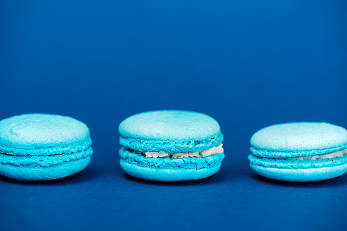 tasty french macaroons on blue background with copy space