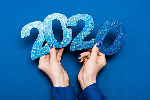 cropped view of woman holding 2020 numbers on blue background