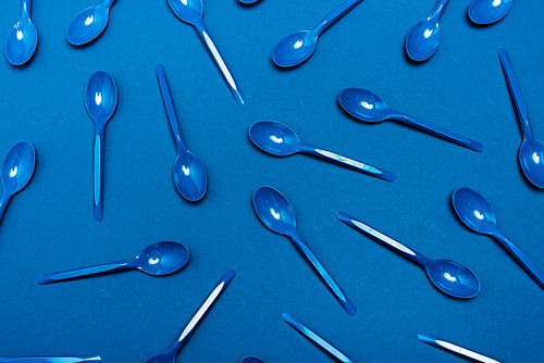 top view of plastic spoons on blue background