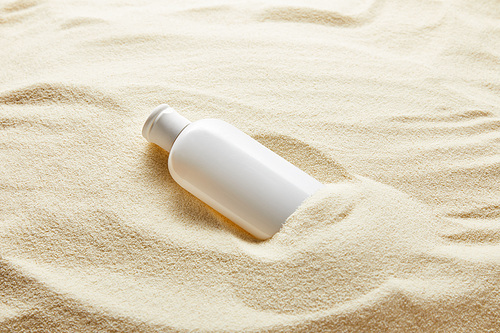 sunblock moisturizing lotion in white bottle in sand