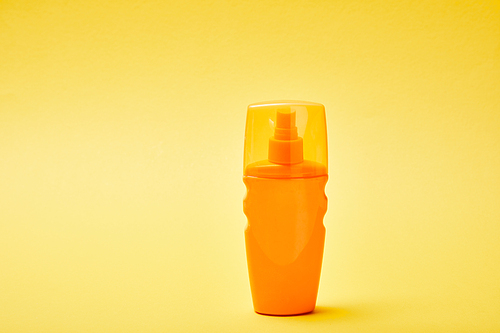 sunscreen in orange bottle on colorful yellow background