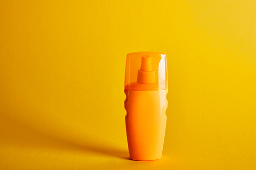 sunscreen in orange bottle on dark yellow background