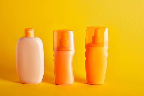 suntan cosmetics in bottles on dark yellow background