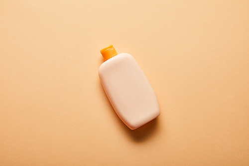 top view of sunscreen lotion in bottle on beige background