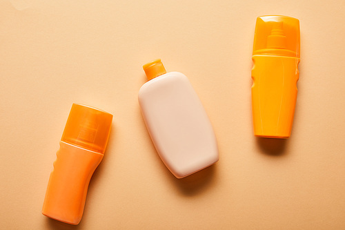 top view of sunscreen products in bottles on beige background