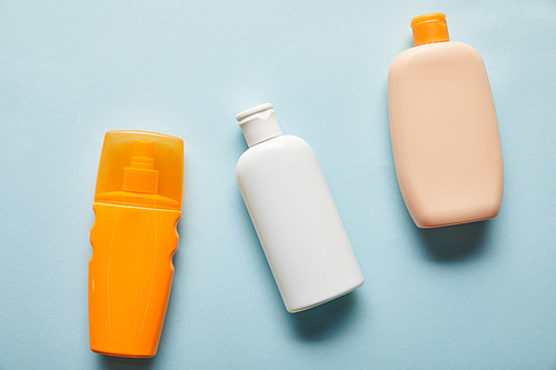 top view of sunscreen products in bottles on blue background