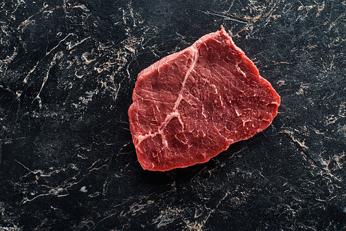top view of uncooked beef sirloin on black marble background