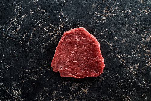 top view of raw meat steak on black marble surface