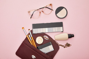 top view of glasses near bag with decorative cosmetics isolated on pink