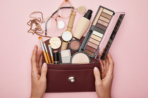 top view of woman near bag with decorative cosmetics isolated on pink