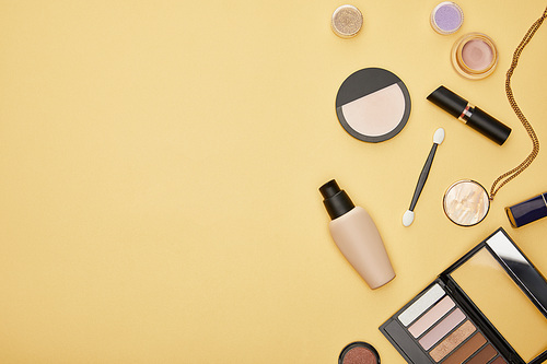 top view of face foundation and eye shadow isolated on yellow