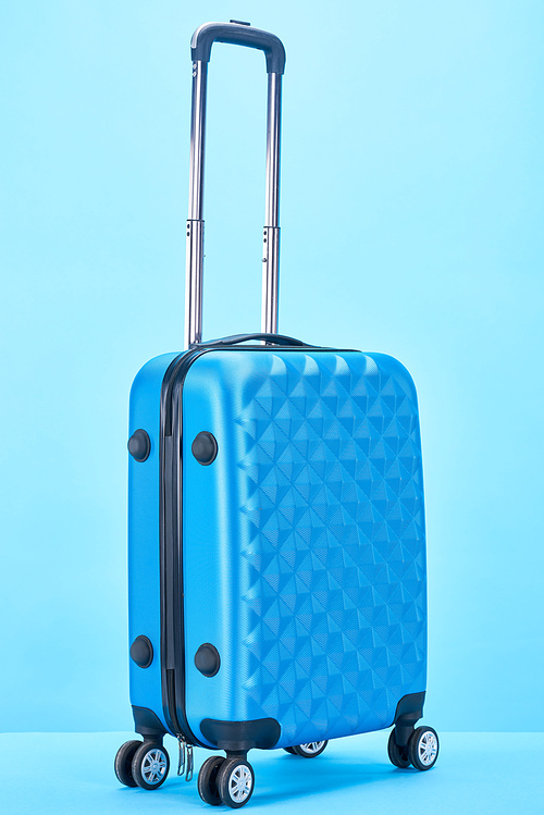 blue travel bag with handle on wheels on blue background