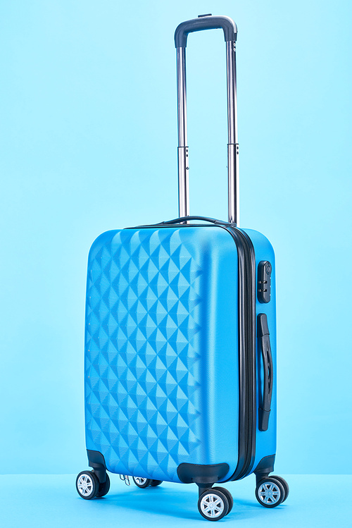 blue colorful suitcase with handle on wheels on blue background