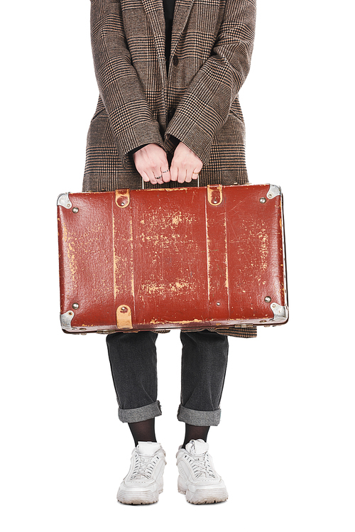 cropped view of woman in plaid coat holding vintage weathered suitcase isolated on white