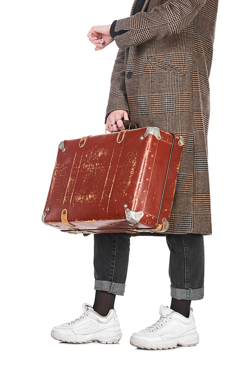 cropped view of woman in plaid coat holding vintage weathered suitcase and checking time isolated on white
