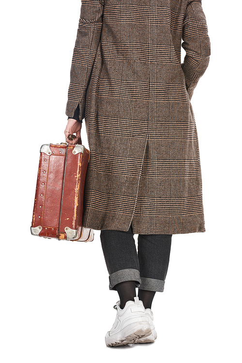 back view of woman in plaid coat holding vintage weathered suitcase isolated on white