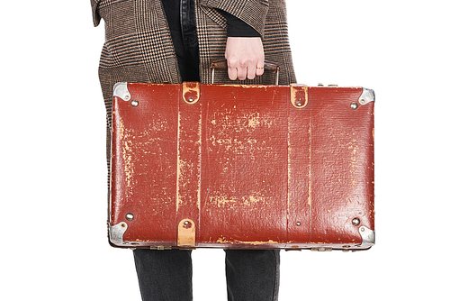 partial view of woman in plaid coat holding vintage weathered suitcase isolated on white
