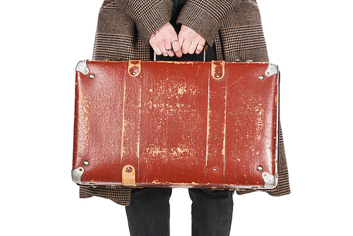 partial view of woman in checkered coat holding vintage weathered suitcase isolated on white