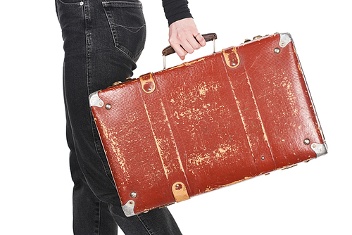 cropped view of girl in jeans holding vintage weathered suitcase isolated on white