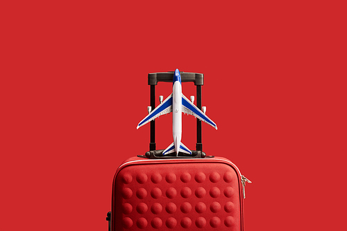 red colorful textured travel bag with plane model isolated on red