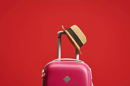 colorful travel bag with straw hat isolated on red