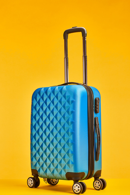 blue plastic travel bag with handle on wheels isolated on orange