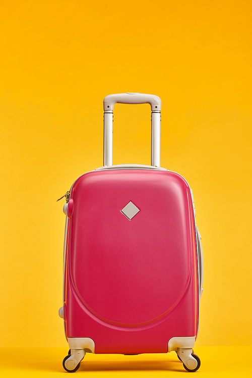red travel bag with handle on wheels isolated on orange