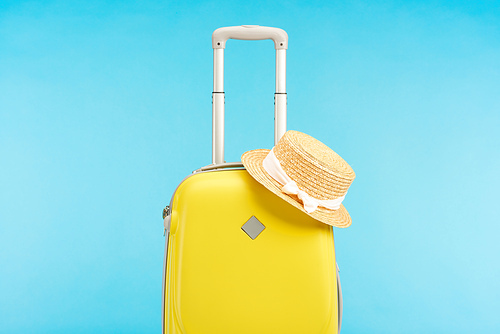 yellow colorful travel bag with straw hat isolated on blue