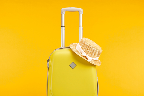 yellow colorful travel bag with straw hat isolated on yellow