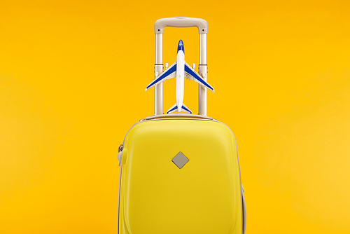 yellow colorful travel bag with toy plane isolated on yellow