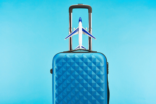 blue colorful travel bag with handle and toy plane isolated on blue