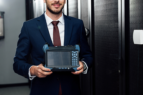cropped view of happy businessman holding reflectometer in server room
