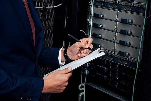 cropped view of man in suit holding clipboard and pen in data center