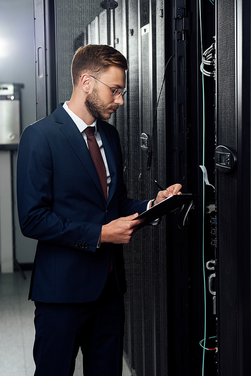 handsome businessman in suit holding clipboard and pen in data center